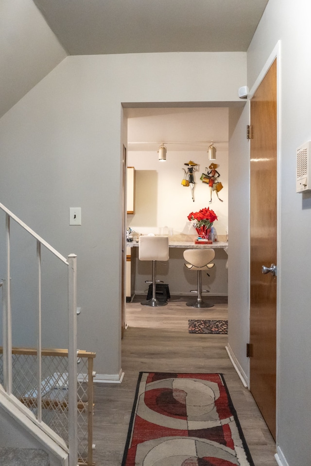 corridor with baseboards, lofted ceiling, stairs, and wood finished floors