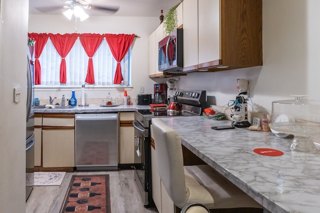 kitchen featuring a sink, light wood-type flooring, stainless steel appliances, white cabinets, and ceiling fan