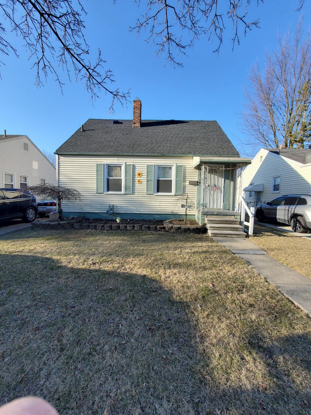 view of front of house with a chimney, a shingled roof, and a front lawn