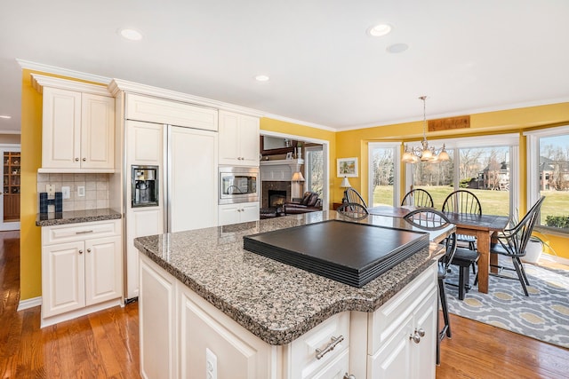 1615 Royal Birkdale Dr, Oxford, MI 48371 - kitchen featuring ornamental molding, a kitchen island, light wood-style floors, built in appliances, and a notable chandelier