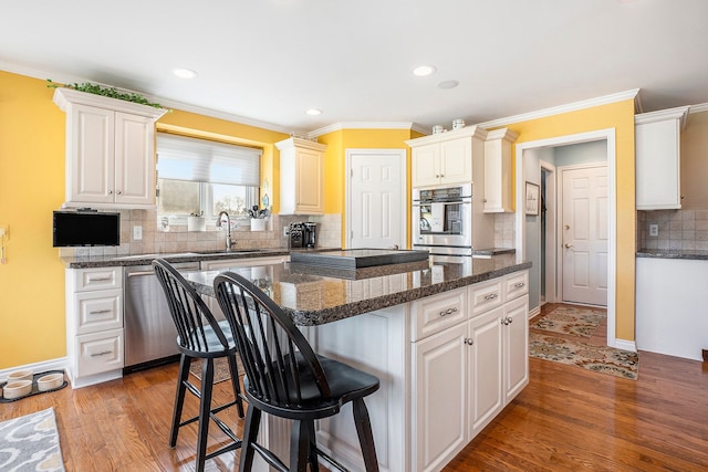 1615 Royal Birkdale Dr, Oxford, MI 48371 - kitchen featuring wood finished floors, a kitchen island, stainless steel dishwasher, a sink, and a kitchen breakfast bar