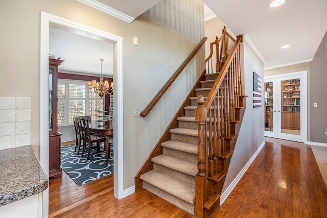 1615 Royal Birkdale Dr, Oxford, MI 48371 - stairway featuring crown molding, french doors, an inviting chandelier, baseboards, and wood finished floors