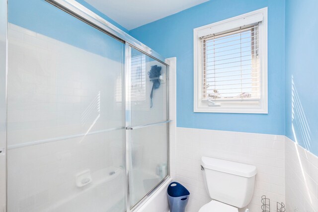 1615 Royal Birkdale Dr, Oxford, MI 48371 - full bath featuring tile walls, toilet, shower / bath combination with glass door, and wainscoting
