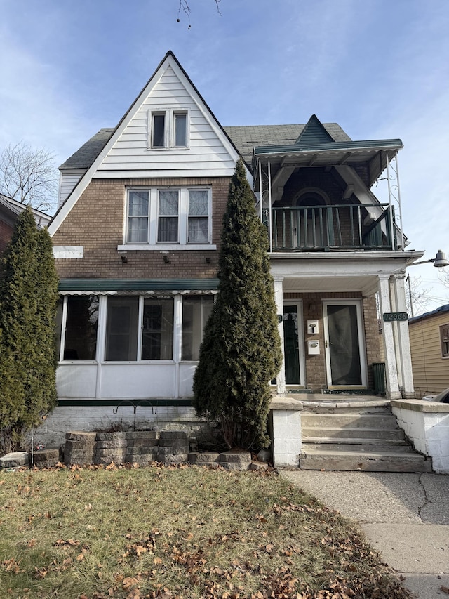 view of front facade featuring covered porch, brick siding, and a balcony