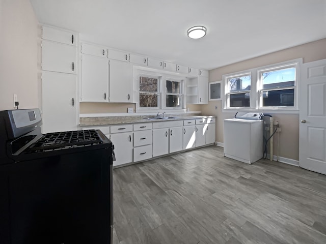 1927 Jarvis Ave, Warren, MI 48091 - kitchen featuring gas stove, washer / dryer, light countertops, white cabinetry, and light wood-type flooring