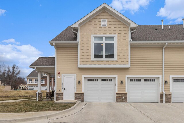 616 Boardwalk Ln Unit 24, Dexter, MI 48130 - view of property featuring stone siding, a shingled roof, a garage, and driveway