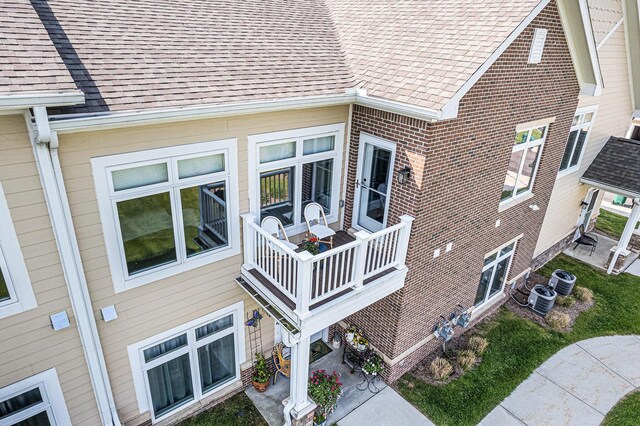 616 Boardwalk Ln, Dexter, MI 48130 - view of home's exterior featuring a balcony, cooling unit, roof with shingles, and brick siding