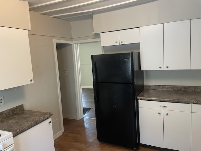 1776 Mcilwrath St, Muskegon, MI 49442 - kitchen featuring freestanding refrigerator, dark countertops, dark wood-style floors, white cabinets, and tile walls