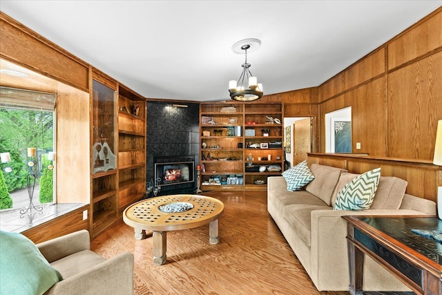 2865 Steeple Hill Rd, White Lake, MI 48383 - living area featuring wooden walls, a chandelier, built in features, light wood-style flooring, and a fireplace