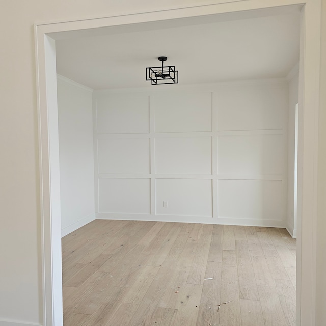 55834 Stewart Dr, Macomb, MI 48042 - unfurnished dining area with light wood-type flooring, a decorative wall, and crown molding