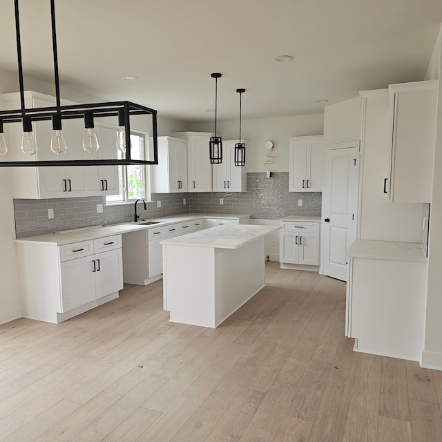 55834 Stewart Dr, Macomb, MI 48042 - kitchen featuring a sink, tasteful backsplash, light wood-style floors, pendant lighting, and a kitchen island