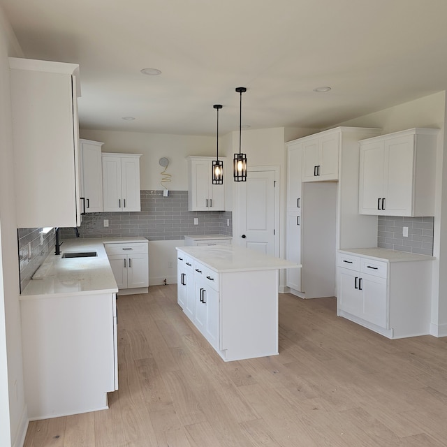 55834 Stewart Dr, Macomb, MI 48042 - kitchen with a sink, backsplash, light wood finished floors, hanging light fixtures, and white cabinets