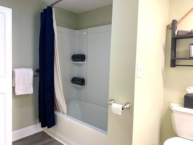 full bathroom featuring baseboards, wood finished floors, toilet, and shower / bath combo with shower curtain