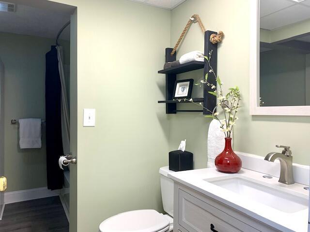 full bath featuring vanity, toilet, baseboards, visible vents, and wood finished floors