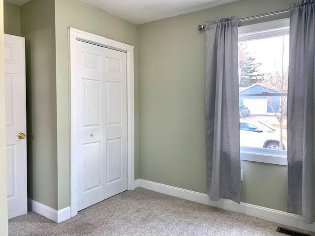 unfurnished bedroom with carpet flooring, a closet, and visible vents