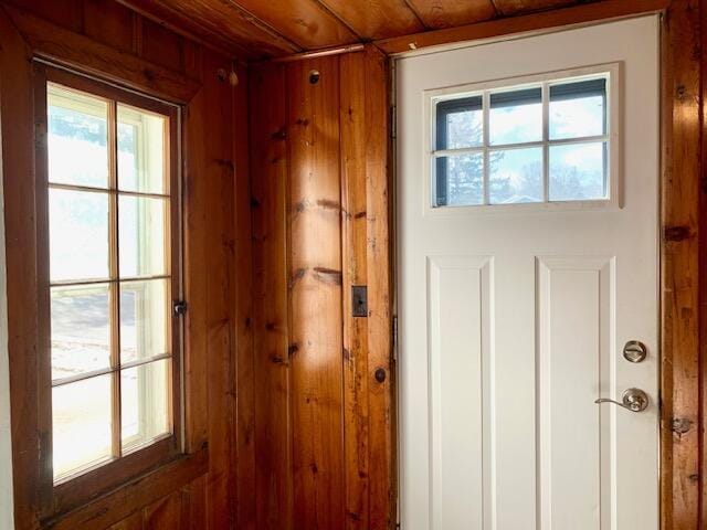 doorway featuring wood walls, wooden ceiling, and plenty of natural light