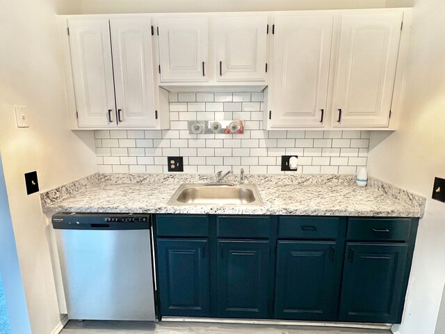 kitchen with stainless steel dishwasher, a sink, decorative backsplash, and white cabinetry
