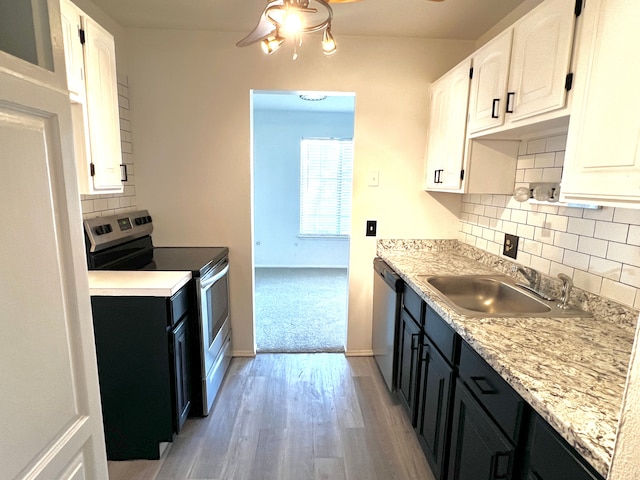 kitchen with stainless steel appliances, white cabinetry, a sink, and dark cabinetry