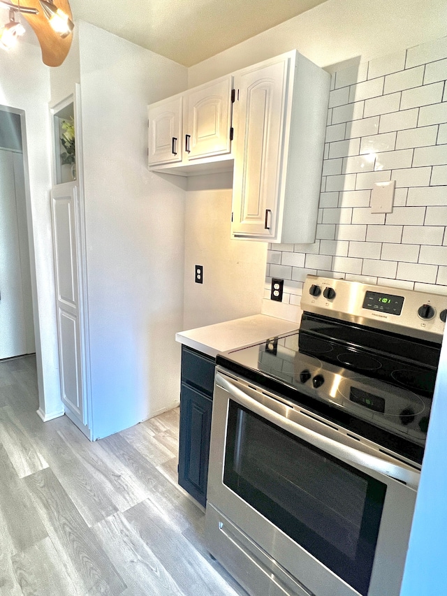 kitchen featuring stainless steel range with electric cooktop, tasteful backsplash, light wood finished floors, light countertops, and white cabinetry