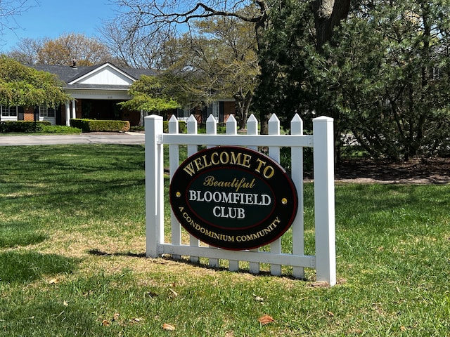 community sign with a lawn, fence, and driveway