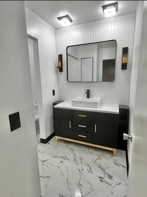 bathroom with vanity, marble look tile flooring, and toilet