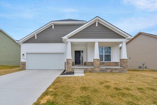 craftsman inspired home featuring concrete driveway, stone siding, a front yard, covered porch, and a garage