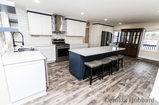 11724 N Satterlee Rd, Lakeview, MI 48850 - kitchen featuring wall chimney range hood, appliances with stainless steel finishes, a sink, a breakfast bar area, and a kitchen island