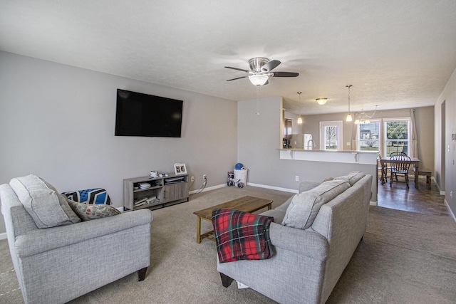 carpeted living room featuring baseboards and ceiling fan