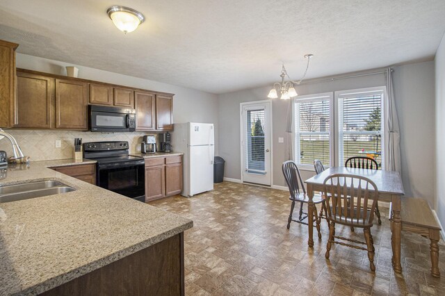 kitchen featuring light countertops, a sink, tasteful backsplash, and black appliances