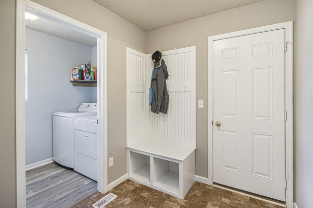 mudroom featuring baseboards, separate washer and dryer, and visible vents