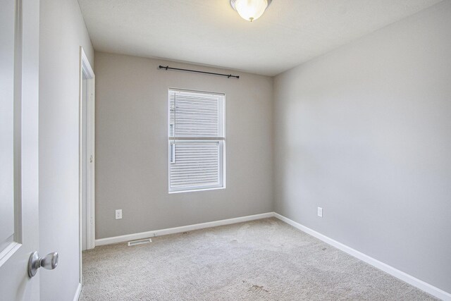 empty room with baseboards, visible vents, and carpet