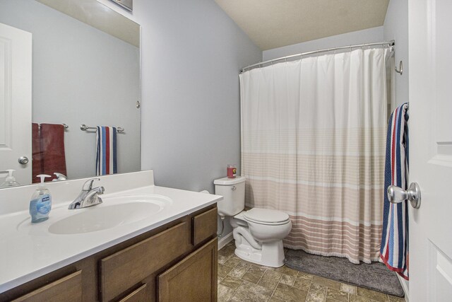 full bath featuring toilet, vanity, stone finish flooring, and a shower with shower curtain
