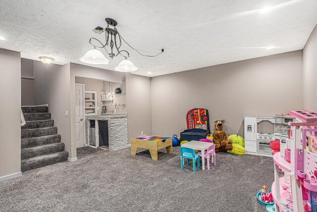 recreation room featuring baseboards, carpet flooring, and a textured ceiling