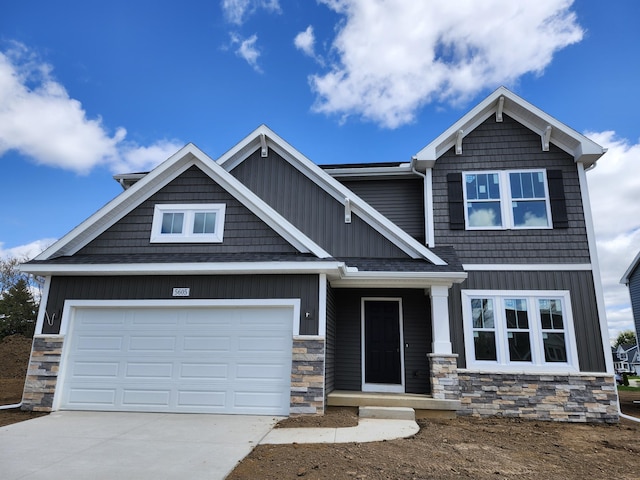 craftsman house featuring driveway, stone siding, board and batten siding, and a garage