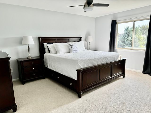 bedroom featuring light colored carpet, ceiling fan, and baseboards