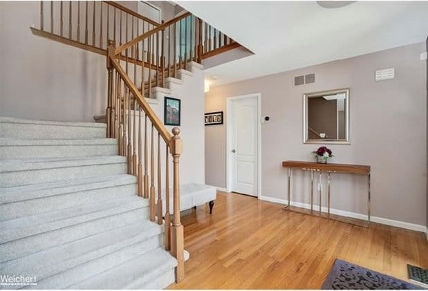 stairway with baseboards, visible vents, and wood finished floors