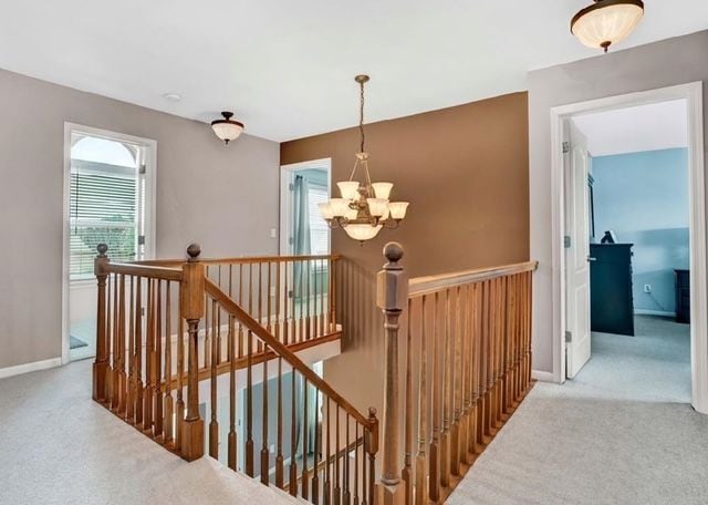 staircase with an inviting chandelier, carpet floors, and baseboards