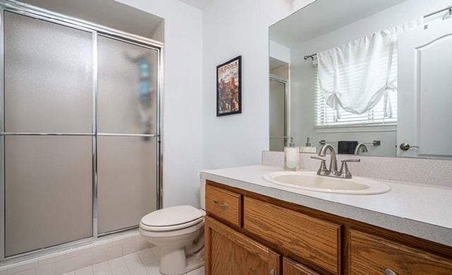 bathroom with a shower stall, tile patterned floors, toilet, and vanity