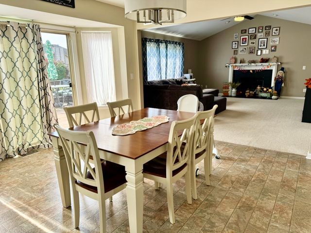 carpeted dining area with vaulted ceiling