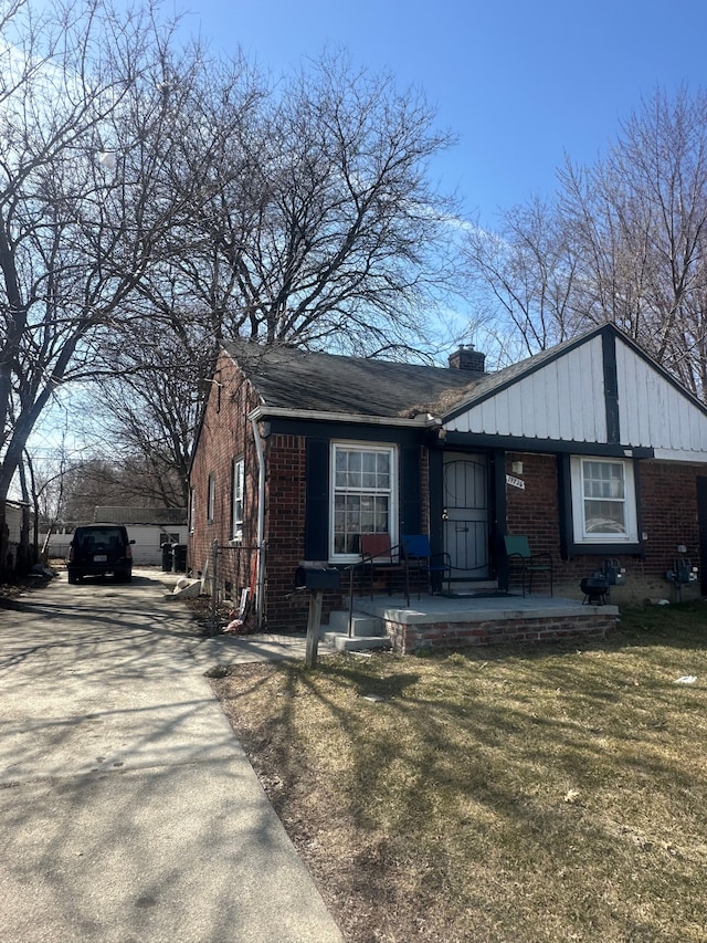 19726 Moross Rd, Detroit, MI 48224 - view of front of home featuring a front lawn, a chimney, a porch, and brick siding