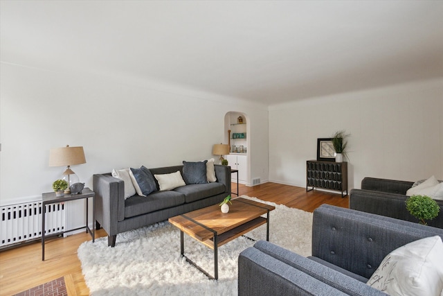 21124 Thorofare Rd, Grosse Ile, MI 48138 - living area with radiator heating unit, wood finished floors, arched walkways, and visible vents
