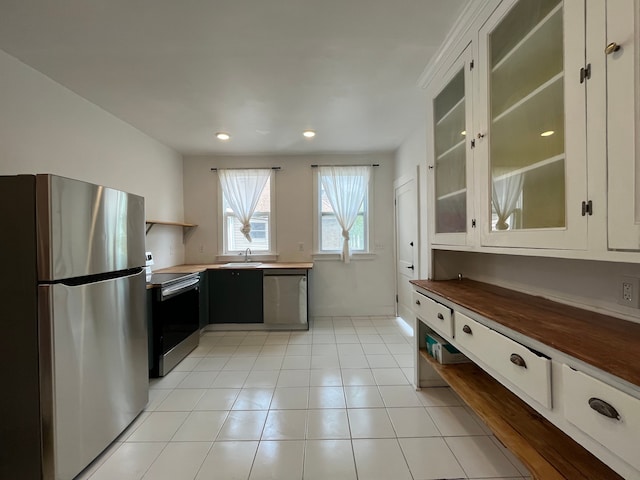 2563 Canton St, Detroit, MI 48207 - kitchen with wood counters, appliances with stainless steel finishes, glass insert cabinets, a sink, and light tile patterned floors
