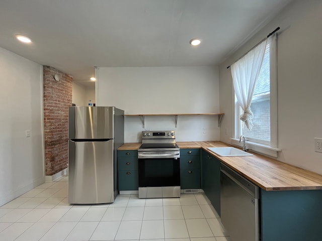 2563 Canton St, Detroit, MI 48207 - kitchen featuring light tile patterned flooring, wooden counters, appliances with stainless steel finishes, a sink, and open shelves