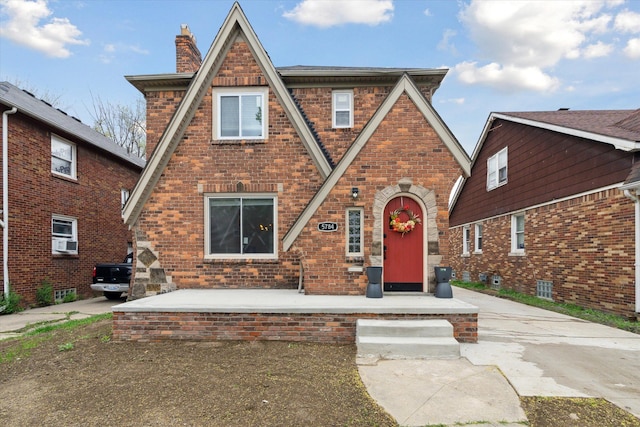 5784 Whittier St, Detroit, MI 48224 - tudor home featuring a chimney, cooling unit, and brick siding