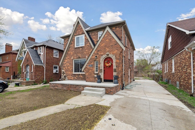 5784 Whittier St, Detroit, MI 48224 - tudor home featuring driveway, covered porch, and brick siding