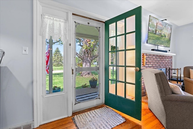 3440 Crandall Rd, Howell, MI 48855 - doorway with hardwood / wood-style floors and a brick fireplace