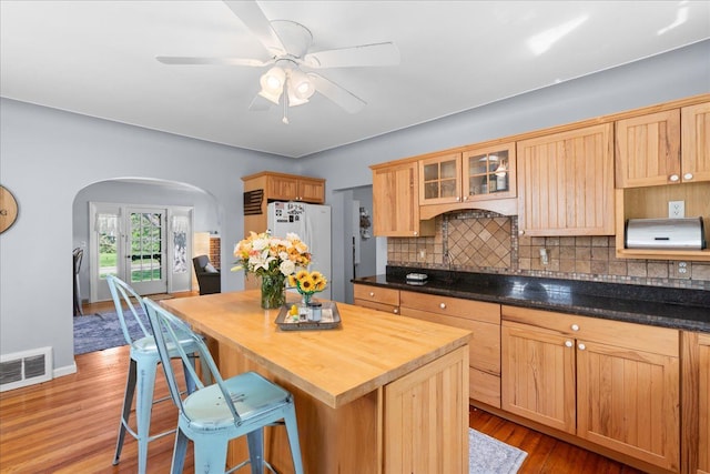 3440 Crandall Rd, Howell, MI 48855 - kitchen featuring backsplash, freestanding refrigerator, arched walkways, light wood-style floors, and a breakfast bar