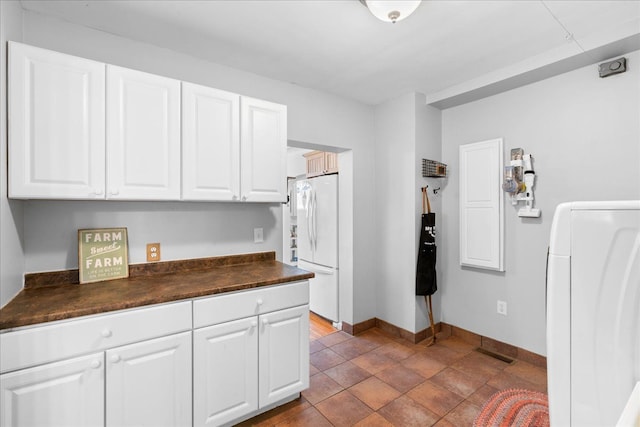 3440 Crandall Rd, Howell, MI 48855 - kitchen with washer / dryer, dark countertops, freestanding refrigerator, and white cabinetry