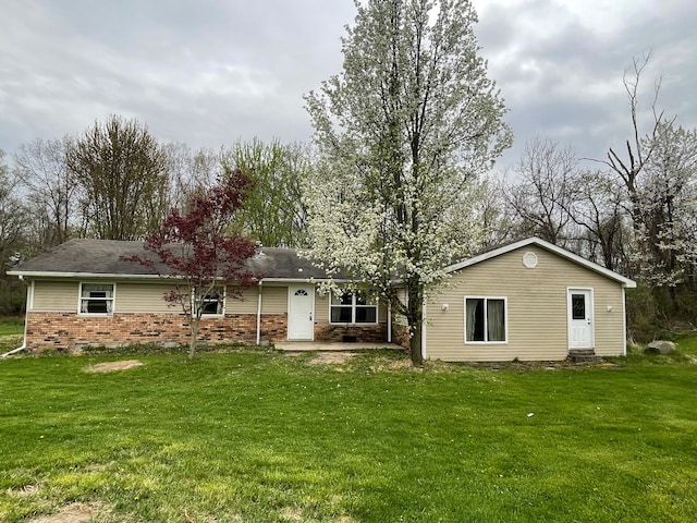 rear view of house with a patio, a yard, and brick siding