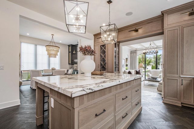557 Greenwood Ave SE, East Grand Rapids, MI 49506 - kitchen with a notable chandelier, light stone countertops, a kitchen bar, a center island, and decorative light fixtures